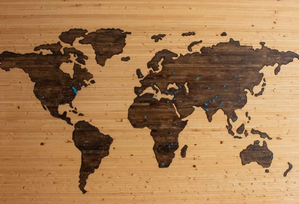 World map made of wood with pins in different countries.